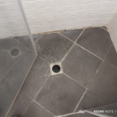 רצפת מקלחת עם ניקוז פתוח ואריחים אפורים