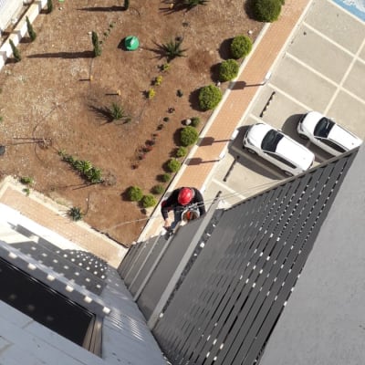 אדם עם קסדה אדומה עובד בגובה על קיר בניין