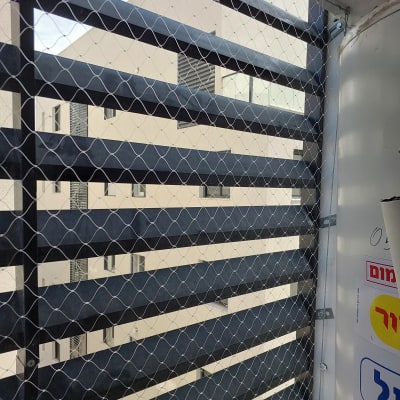 רשת מתכת מותקנת על סורגי חלון למניעת כניסת יונים.