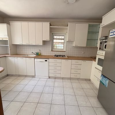 מטבח עם ארונות לבנים ומכשירי חשמל