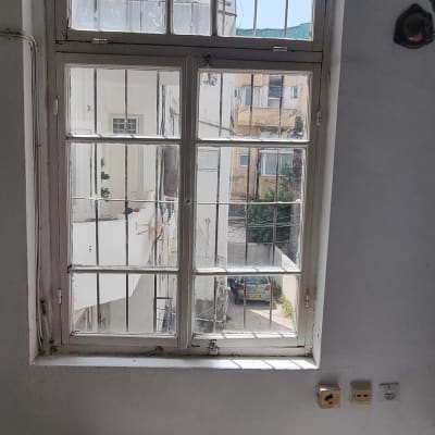 חלון עם סורגים ומבנים חיצוניים ברקע