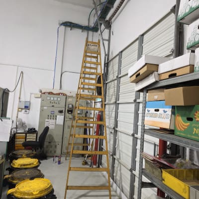 סולם ליד דלת חשמלית במחסן עם ציוד וכלים
