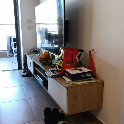 טלוויזיה על קיר עם מדף, נעליים ופירות