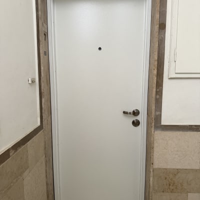 דלת לבנה עם ידית מתכת במסגרת אבן