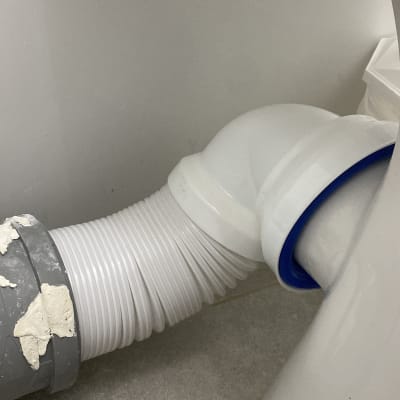 צינור פלסטיק מתחת לכיור עם חיבורי מתכת