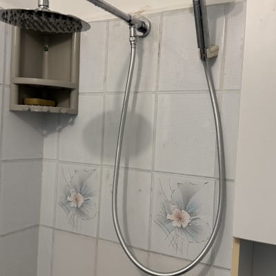 ראש מקלחת וכפתורי מים על קיר אריחים