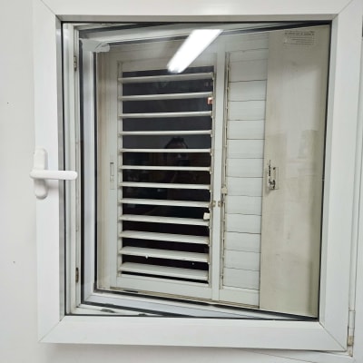 חלון עם תריסים לבנים על קיר לבן