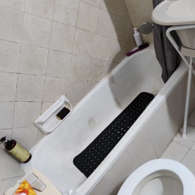 אמבטיה עם שטיחון שחור, בקבוק סבון ומברשת שיער