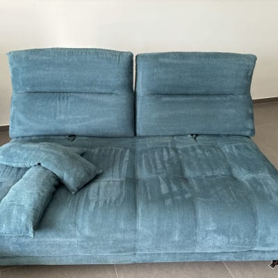 ספה כחולה עם כריות על רצפת אריחים אפורה