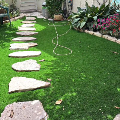 אבנים משתלבות על דשא סינתטי עם צינור השקיה