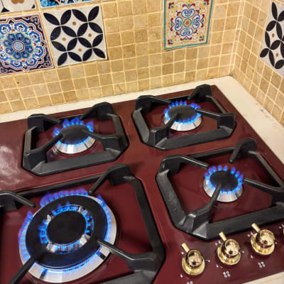 כיריים גז עם להבות כחולות ואריחים מעוצבים ברקע