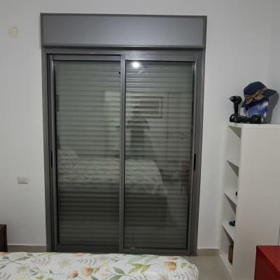 חדר שינה עם תריסים סגורים ומיטה