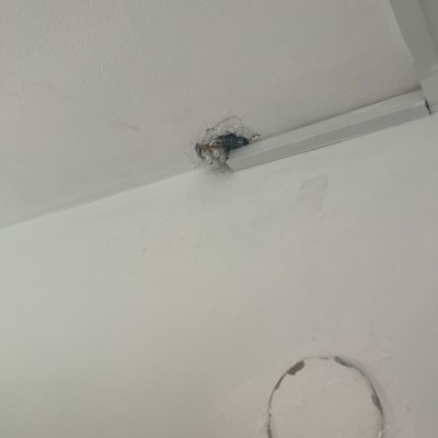 חוטי חשמל יוצאים מהתקרה ליד תעלה לבנה