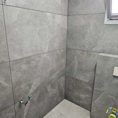 חדר אמבטיה עם אריחים אפורים, צינורות חשופים