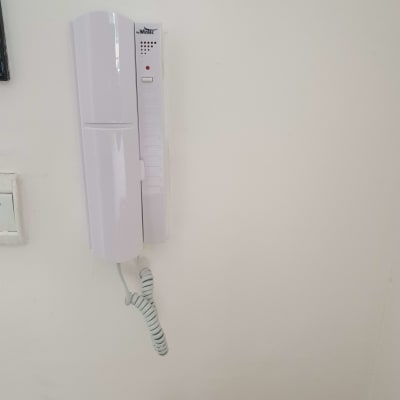 אינטרקום לבן עם שפופרת תלויה על הקיר