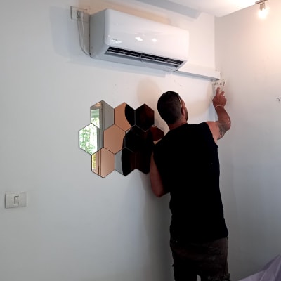 אדם מתקין מזגן על קיר לבן בחדר