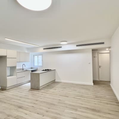 מטבח מודרני עם ארונות לבנים ומשטח עבודה אפור