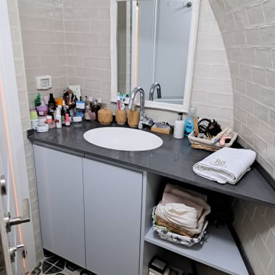 חדר אמבטיה מאורגן עם כיור, מראה ומדפים מסודרים.