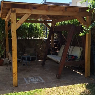 פרגולה מעץ עם נדנדה בגינה