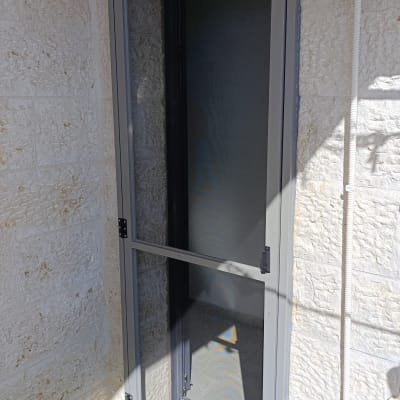 דלת אלומיניום אפורה עם רשת על מרפסת