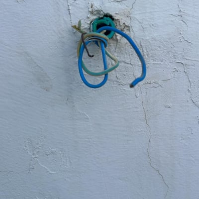 חוטי חשמל יוצאים מקיר עם חור