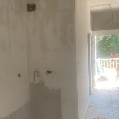 שיפוץ קיר עם חוטי חשמל חשופים וחלקי בנייה על הרצפה