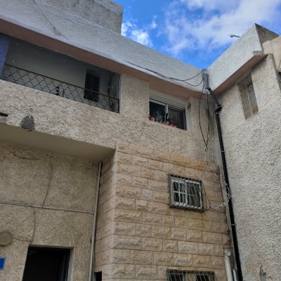 בניין מגורים עם קירות אבן וחלונות סורגים.