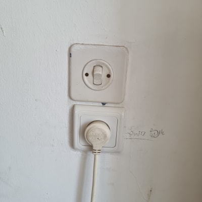 שקע חשמל עם תקע מחובר לקיר לבן