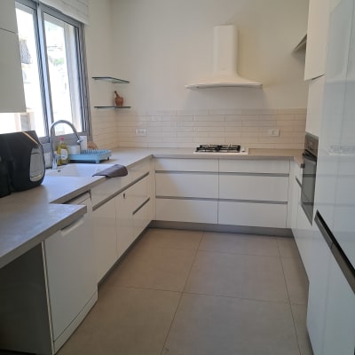 מטבח מודרני עם ארונות לבנים וכיור ליד חלון