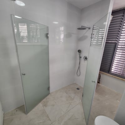 מקלחת עם דלתות זכוכית וראש מקלחת עגול