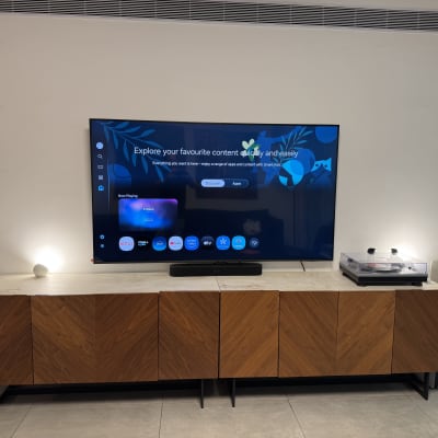 טלוויזיה מותקנת על קיר עם רמקולים ומדף עץ