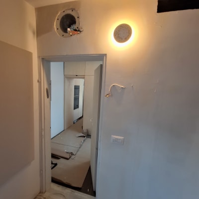 קיר צבוע עם חור ותאורה, חוטים על הרצפה