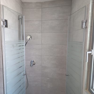 מקלחת עם דלתות זכוכית וראש מקלחת כסוף