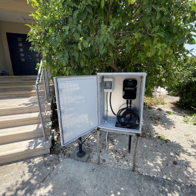 ארון חשמל פתוח עם כבלים ליד עץ ירוק