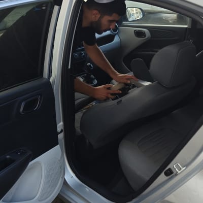 אדם מנקה מושב רכב עם מכשיר ניקוי