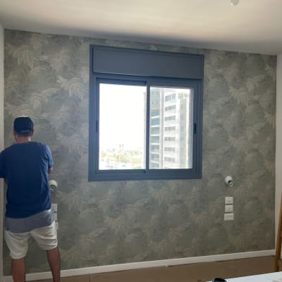 אדם מתקין טפט עם דוגמת עלים על קיר