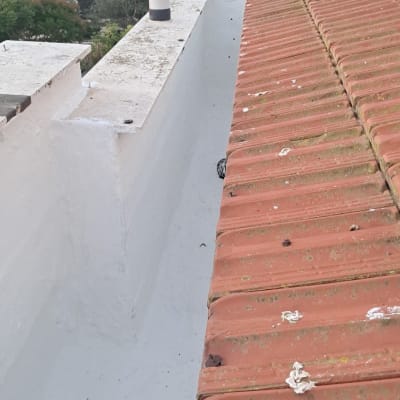 גג רעפים אדומים עם תעלת ניקוז לבנה