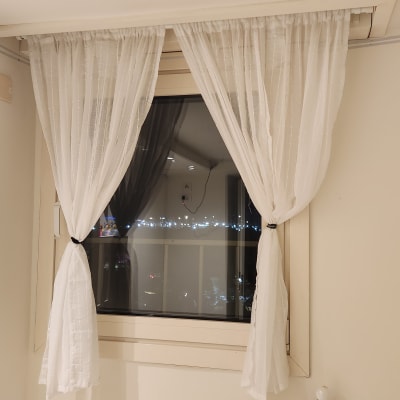 וילון לבן תלוי על חלון עם נוף לילי