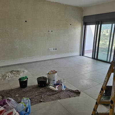 חדר בשיפוץ עם קיר חשוף, דלי צבע וסולם