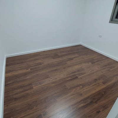 רצפת פרקט עץ כהה בחדר ריק עם קירות לבנים