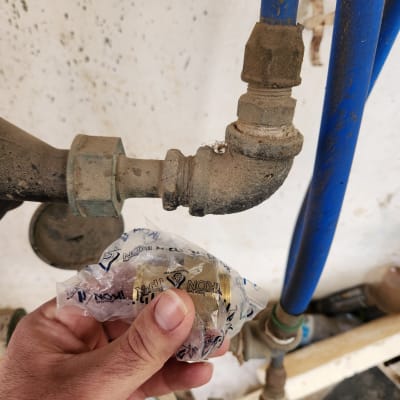 יד מחזיקה חלק פלסטיק ליד צינורות מים כחולים