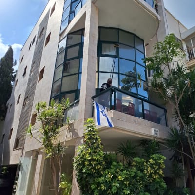 אדם מנקה חלונות עם מוט ארוך בבניין