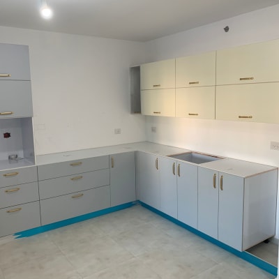 מטבח חדש עם ארונות אפורים ולבנים, ללא שיש.