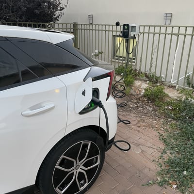 רכב חשמלי מחובר לעמדת טעינה בחניה