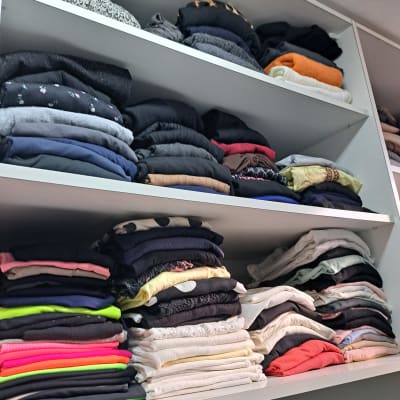 בגדים מקופלים ומסודרים על מדפים בארון