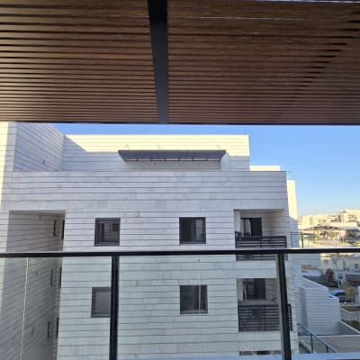 פרגולה מאלומיניום מעל מרפסת עם נוף לבניין מודרני