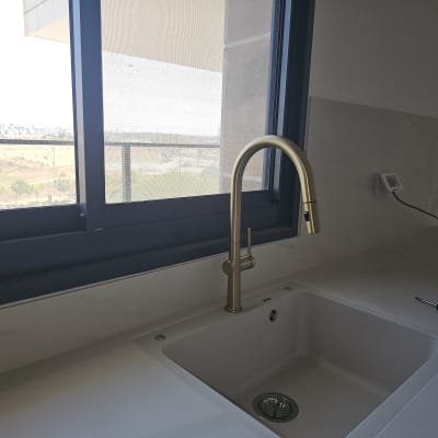 ברז זהב וכיור במטבח ליד חלון