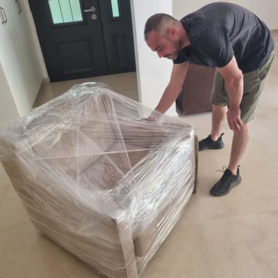 אדם עוטף כורסה בניילון נצמד למעבר דירה