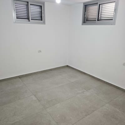 חדר ריק עם רצפת אריחים נקייה וקירות לבנים