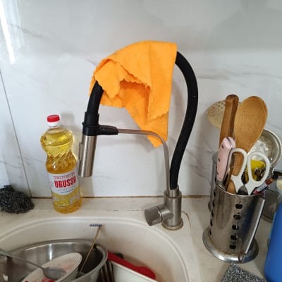 ברז מטבח עם מטלית כתומה תלויה עליו